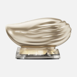 TAFITIE Conch shell-shaped facial device in gold on clear charging base, front view